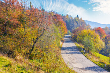 Fototapeta na wymiar old mountain pass in fall season. countryside road trip on a sunny october forenoon. forested hills in colorful foliage