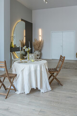 romantic table is served for two in the kitchen in a bright open-plan apartment in a modern style with light walls and wooden floors.