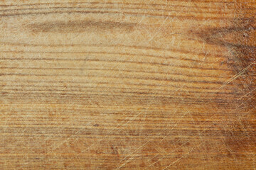 Old light brown textured wooden background. The surface of the scratched cutting board, top view