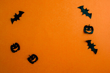 Halloween background, paper black bats and pumpkins on an orange background.