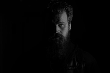 Low key portrait in black and white of a biker wearing his leather vest with president patch on his chest.