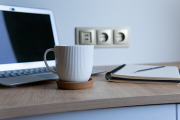 business composition with coffee. a cup of coffee on the background of a notepad and laptop on a wooden table.