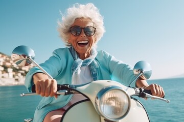 Cheerful senior woman riding blue scooter in Italy, retired granny enjoying summer vacation, trendy bike road trip