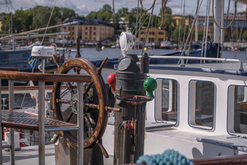 Ships wheel and compass on an old sailing boat at a jetty in the Galärvarvet, a sunny summer day in Stockholm