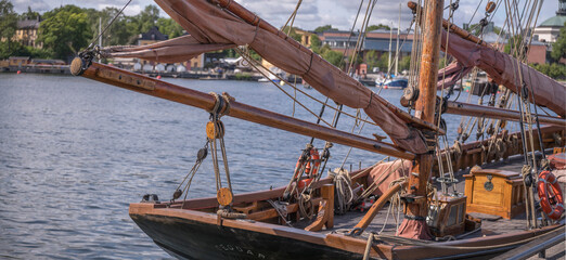 Stern of an old wood sailing boat, masts and booms at the jetty Gal&auml;rvarvet, a sunny summer day in Stockholm