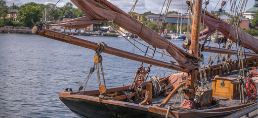 Stern of an old wood sailing boat, masts and booms at the jetty Galärvarvet, a sunny summer day in Stockholm