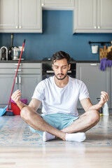 Fototapeta premium Tired man resting on the floor during cleaning house. Household concept