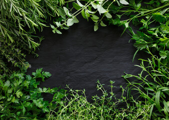 Various of fresh herbs on a black stone background with space for text