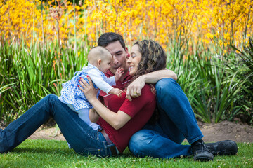 Fototapeta premium Young parents having fun outdoors with their six months old baby girl. Happiness concept. Family concept