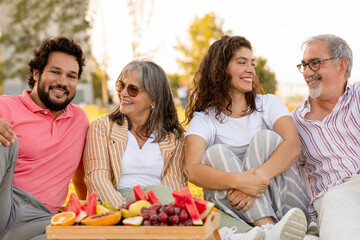 Positive european senior and adult people enjoy picnic, fruits, food in park, outdoor, close up