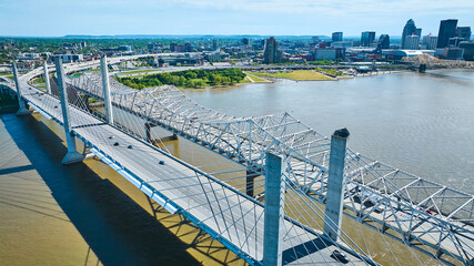 White suspension and truss bridges over dirty water of Ohio River aerial Louisville skyline