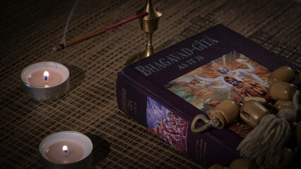 Bhagavad Gita and rosary lying on a wooden table and incense is being smoked. 