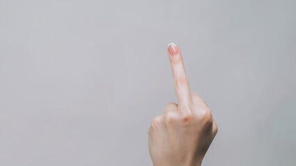 Middle finger. Rude gesture. Woman hand showing impolite sign offensive insulting behavior isolated on gray empty space background.