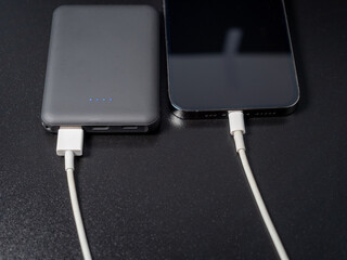 Power bank for charging mobile devices on a black background. Smartphone charger with power supply....