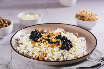 Soft cottage cheese with blackcurrant and walnuts on a breakfast plate