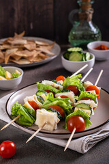 Snack on skewers of tomatoes, cucumber, cheese, pita bread and lettuce on a plate vertical view
