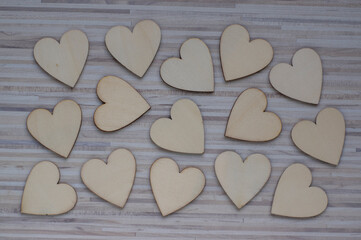 Love Valentines day background, group of light wooden hearts spread on gray striped table, flat lay