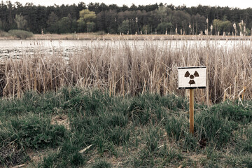 Radiation hazard sign next to a lake with radioactive waste