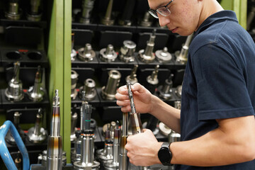 A worker inspects and selects a drill to work on a cnc milling machine.