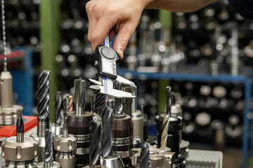 The worker measures the cutters with a caliper to work on milling and turning machines.