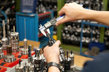 Measuring a cutting tool with a caliper for a CNC machine tool.