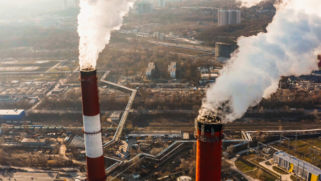 Coal Power Pollution smoking stack. Coal power plant smoking and teaming. Smoke from the pipes in the factory. Power plant smoke stack towers contrast against blue sky background. 