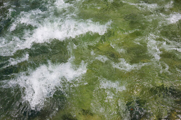 River rapids. Close up abstract background of falling water. Water flows over river rocks. A beautiful powerful stream of a stormy mountain river. The river rushes with fast-flowing water