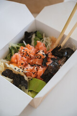 Vertical banner with unrecognizable man eating poke bowl with salmon,seaweed,avocado etc