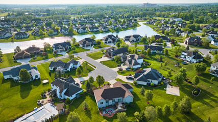 Neighborhood with large homes around pond distant factory on horizon with many trees - obrazy, fototapety, plakaty