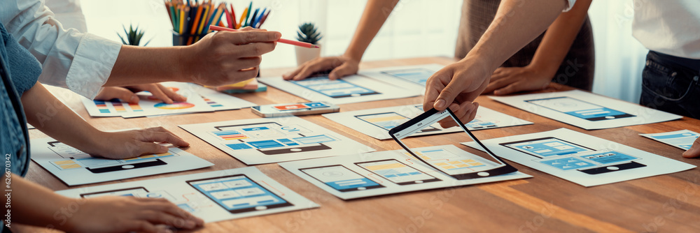 Poster Panorama shot of front-end developer team brainstorming UI and UX designs for mobile app on paper wireframe interface. User interface development team planning for user-friendly UI design. Scrutinize