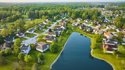 Fototapeta na wymiar Dark blue pond with housing neighborhood and cul-de-sac suburban homes in summer aerial