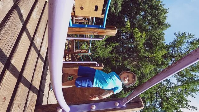 Vertical video - a child straightens clothes on the playground. The concepts of independence, comfort, summer walks, personal hygiene, education, potty training, habits, development, physical activity