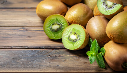 Fresh kiwi gold fruits with mint leaves scattered on rustic wooden table. Whole and cutting kiwi...