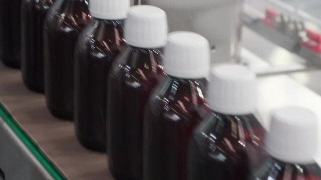 Close-up Many glass bottles for packaging liquid medicines or cosmetics in a row on a conveyor belt in a pharmaceutical manufacturing factory 4K DCI