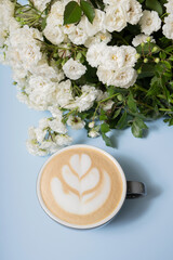 Coffee latte with foam art with flowers top view on blue background. Minimalistic coffee time concept