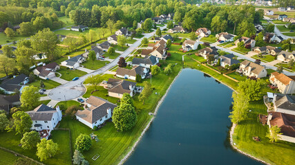 Cul-de-sac aerial suburban neighborhood tree forest skyline in summer around dark blue pond