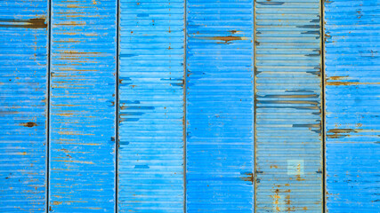 Six various blue pastel colored shipping containers from above, rusting metal crates background