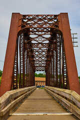 Vertical of metal iron bridge with wooden walking path in summer under cloudy sky
