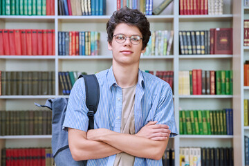 Portrait of confident guy college student looking at camera inside library