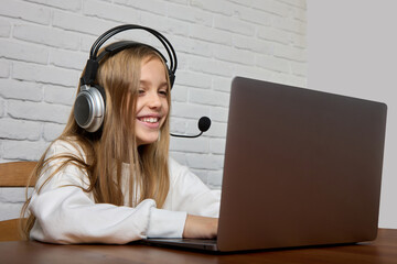 A teenage girl in a headset engages online with a tutor using a laptop. Distance learning of children using modern technologies
