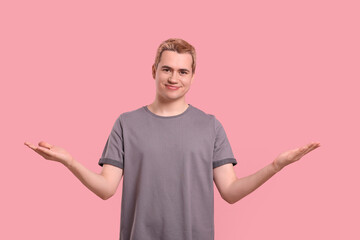 Happy man inviting to come in against pink background