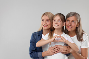 Three generations. Happy grandmother, her daughter and granddaughter on light gray background, space for text