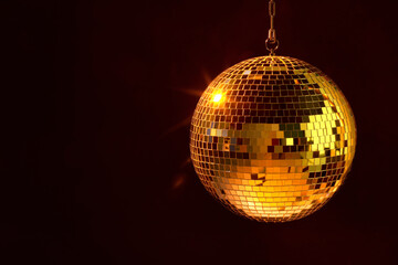 Shiny bright disco ball under orange light, space for text