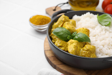 Delicious rice and chicken with curry sauce on white tiled table, closeup. Space for text