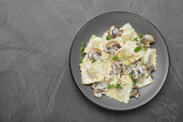 Delicious ravioli with tasty sauce and mushrooms on black table, top view. Space for text