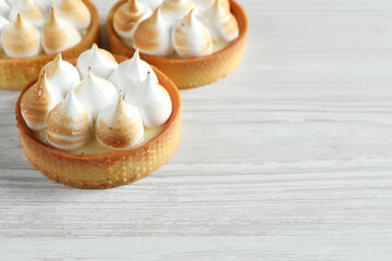 Obraz na płótnie Canvas Tartlets with meringue on white wooden table, closeup. Tasty dessert