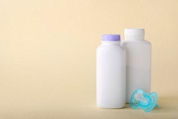 Baby powder in bottles and pacifier on beige background, space for text