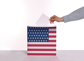 Woman putting her vote into ballot box decorated with flag of USA against white background, closeup