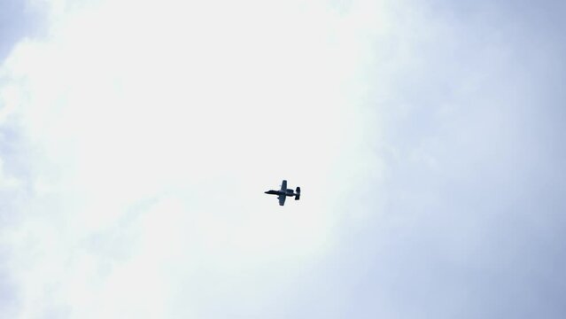 Military jet plane an Air Force gunship in grey color scheme against a blue sky, slow motion
