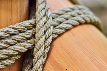 Fototapeta premium Abstract view of close up with thick rope wrapped around shiny bamboo poles